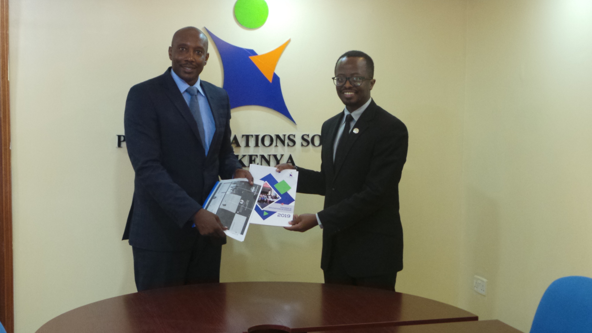 PRSK President exchanges materials with a Nairobi Toastmasters Club official.